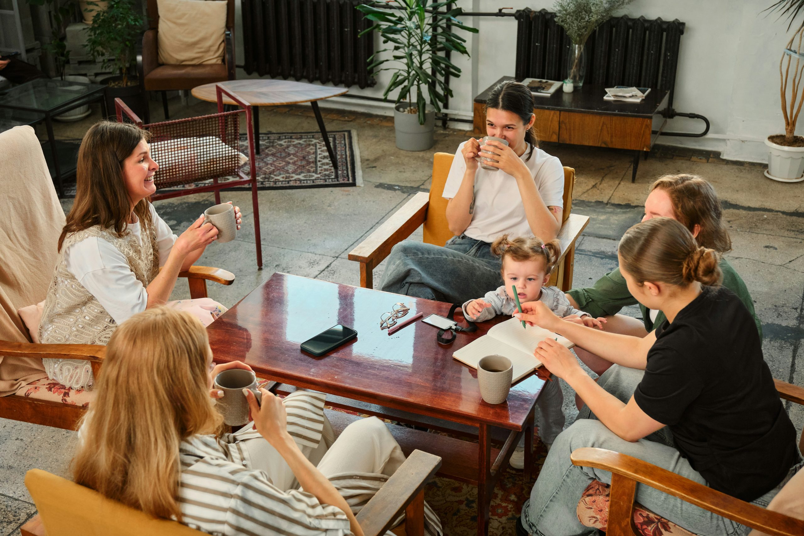 Group of moms drinking coffee together with children