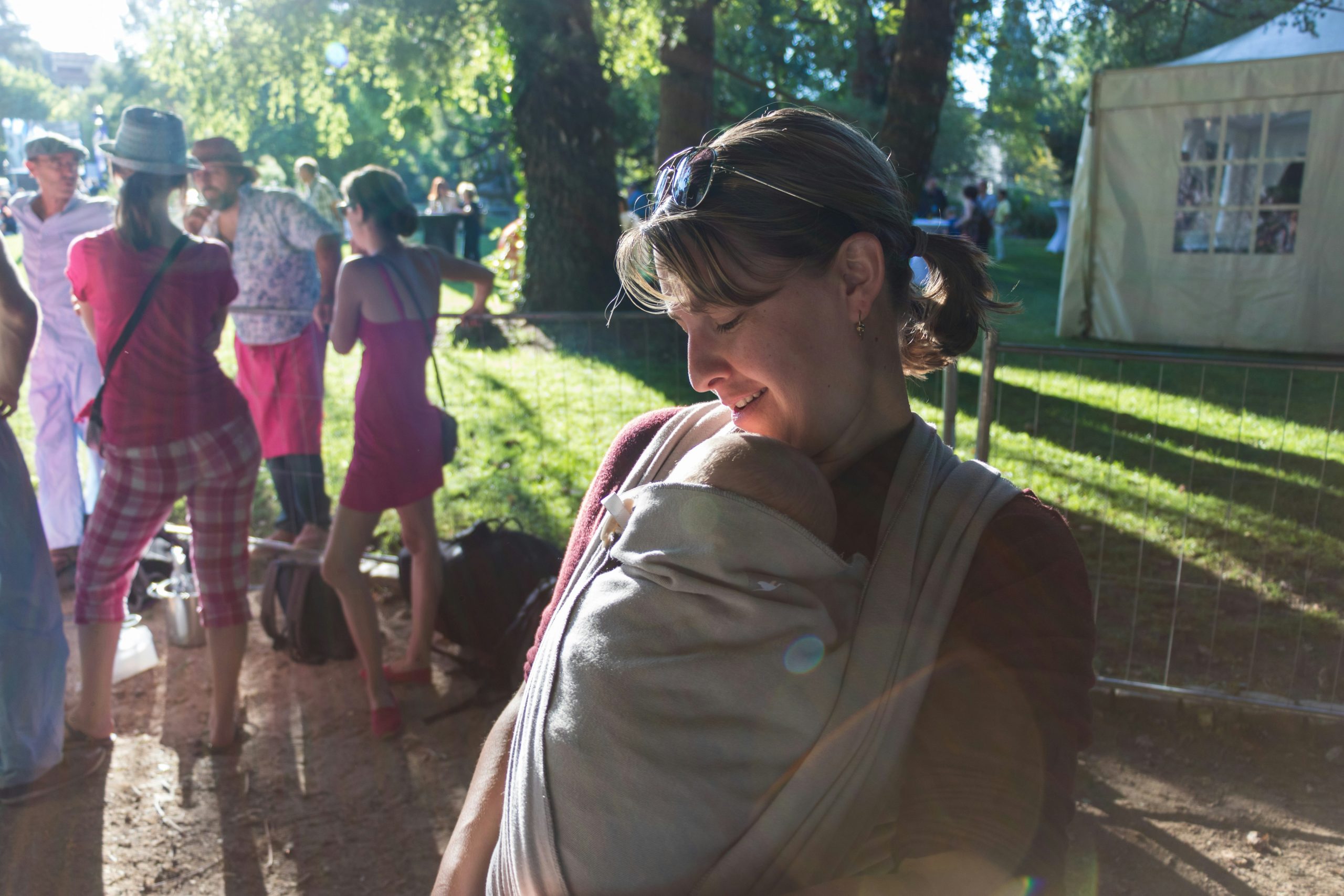 A group of people standing with a mom holding a child in the foreground